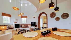 Un vaste espace de vie comprenant une table à manger en bois, plusieurs chaises et un téléviseur.