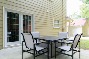 A patio with a table and chairs, a sliding glass door, and a small window.