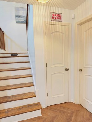 A staircase leading to a door labeled "Game Room" with a "Welcome" sign above it.