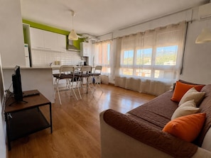 A compact living space with a kitchenette, dining area, and a sofa with cushions.