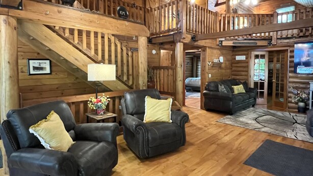 Un interior de madera con dos sillones de cuero, una mesita con una lámpara y una escalera de madera.