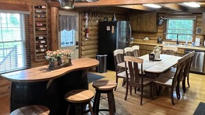 Una cocina rústica con armarios de madera, una isla central con taburetes y una mesa de comedor para seis personas.