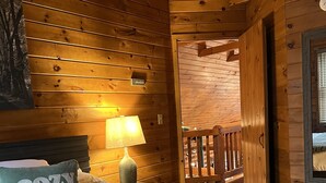 Acogedor dormitorio de cabaña de madera con una cama, una mesita de noche, una lámpara y un letrero que dice 'adventures'.