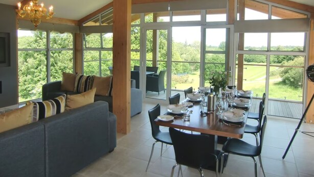 A spacious dining area with a high ceiling and large windows offering a view of the outdoors. - Apple Tree Lodges (Colchester)