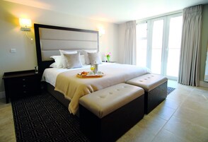 Habitación de hotel con una cama grande, una mesita de noche, una bandeja de desayuno y vistas al exterior.