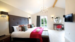 A modern bedroom with a large bed, a red throw blanket, a TV, and a desk with a chair. - Apple Tree Lodges (Colchester)