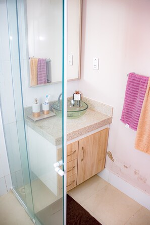 A bathroom with a glass shower enclosure, a glass sink, wooden cabinets, and a mirror above the sink. - Casa de São Pedro da Aldeia (Sao Pedro da Aldeia)