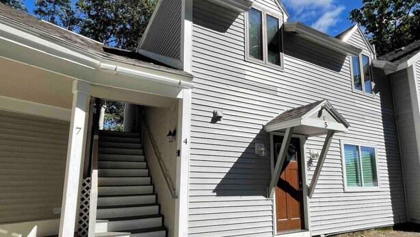 Une maison à deux étages avec un porche et une porte d’entrée.