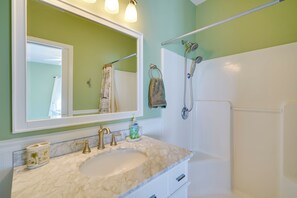 Un baño con lavamanos de mármol, un espejo grande, un perchero y una ducha.