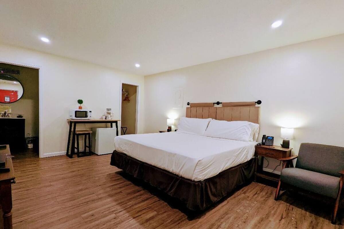 Una habitación de hotel con una cama grande, un escritorio con ordenador, una silla y una pequeña mesa.