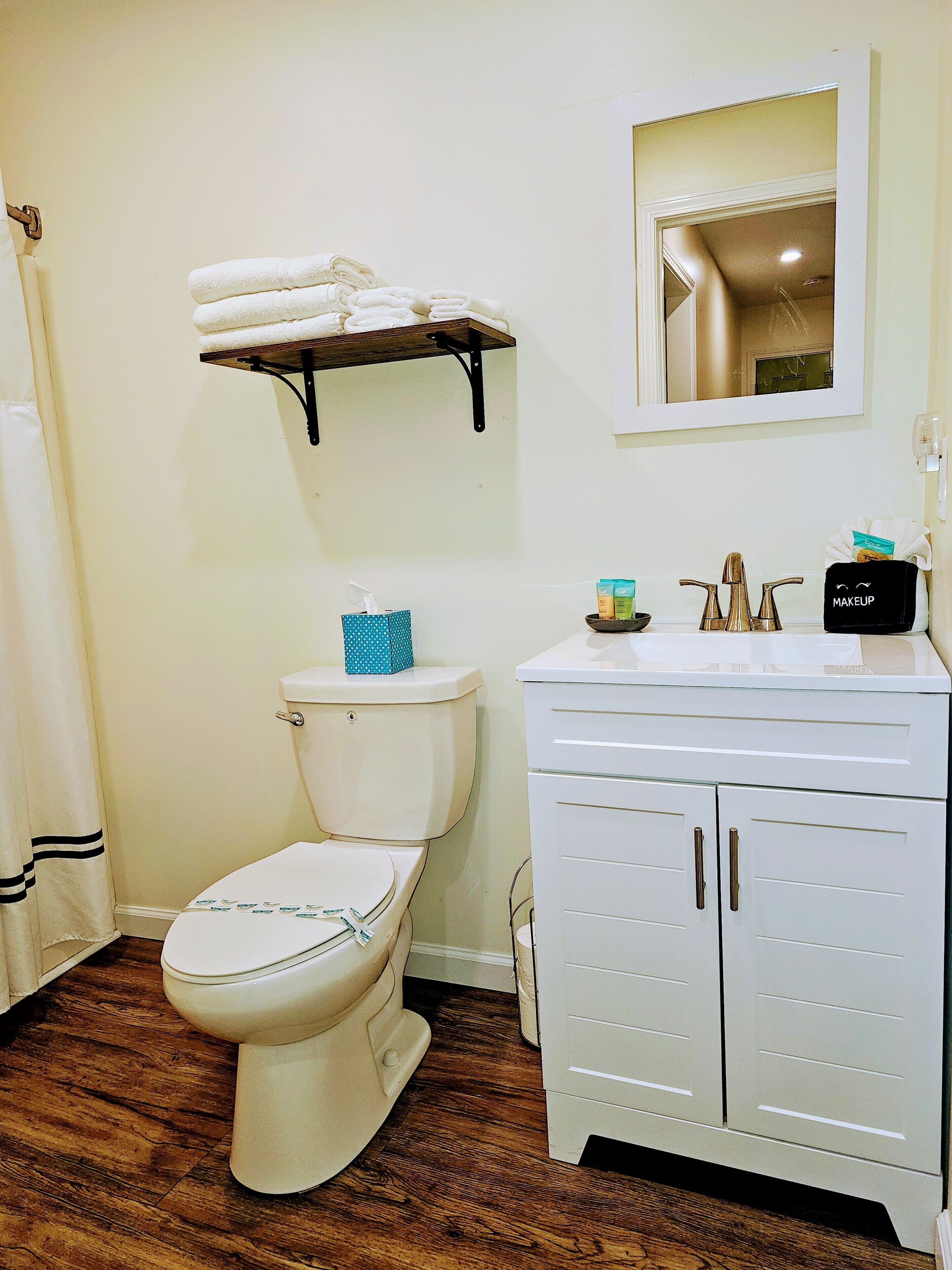 Une salle de bain équipée d’un WC, d’un lavabo, d’un miroir et d’une étagère avec des serviettes.