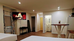 Una habitación de hotel con cama, escritorio, televisor y baño visible a través de una puerta abierta.