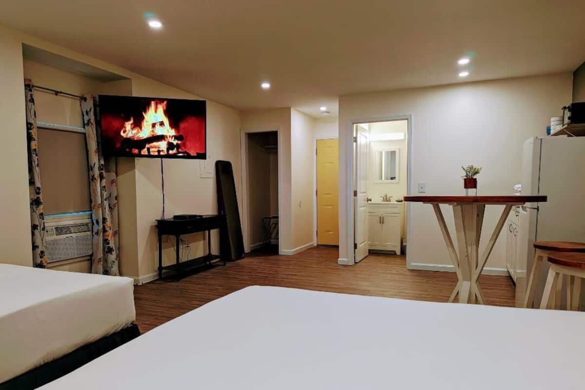 Una habitación de hotel con cama, escritorio, televisor y baño visible a través de una puerta abierta.