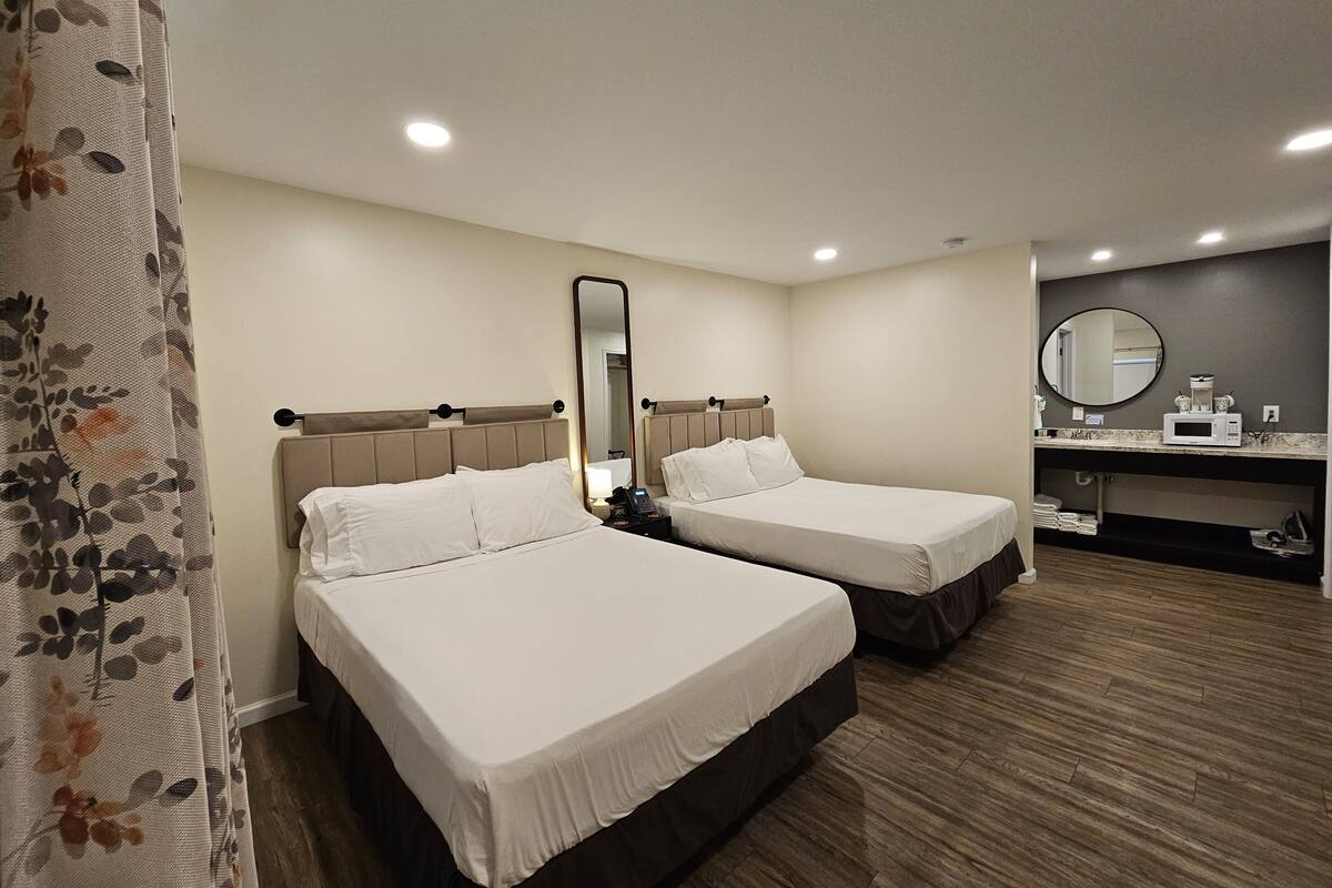 Habitación de hotel con dos camas, baño y kitchenette.