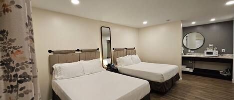 Habitación de hotel con dos camas, baño y kitchenette.