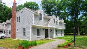 A two-story house with a brick chimney, a front porch, and a driveway.