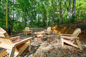 Un espace extérieur boisé, aménagé avec un foyer et des fauteuils Adirondack.