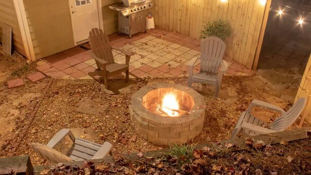 A backyard with a fire pit, wooden chairs, a grill, and string lights. - Private basement w/firepit ideal for longer stays (Suwanee)
