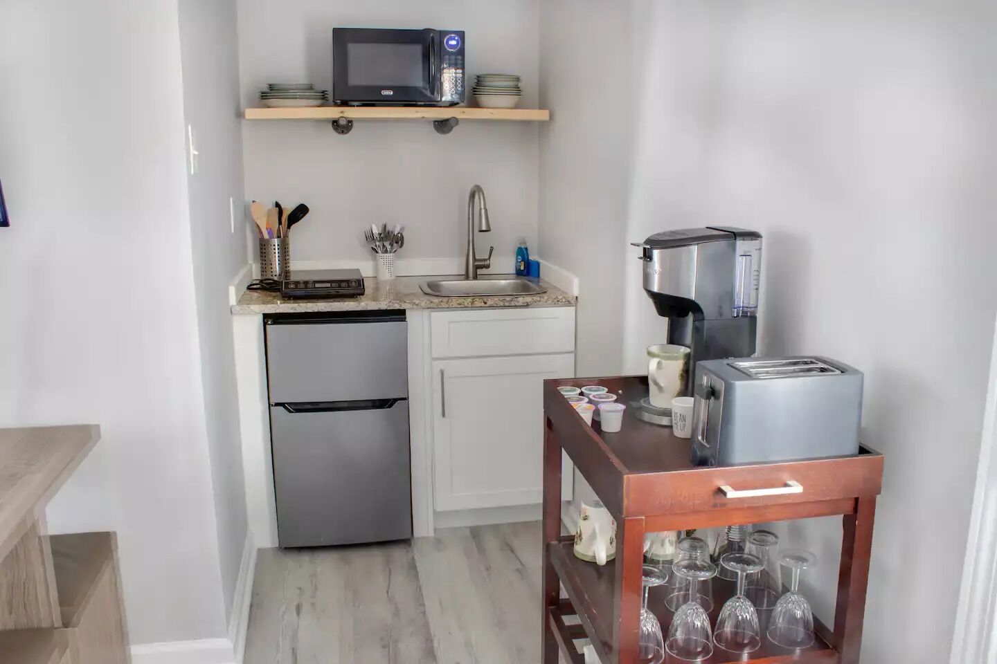 Cocina compacta con microondas, cafetera, tostadora y un refrigerador pequeño.