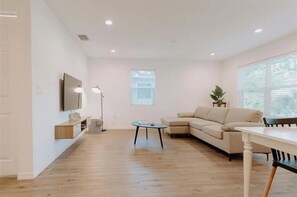 Relax in this stylish living room with a large sofa, flat-screen TV, and a view of the outdoors.