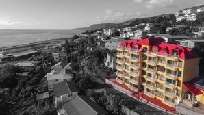 A multi-story hotel with balconies, located near a beach and surrounded by residential buildings. - Bayport Residence Inn (Roseau)