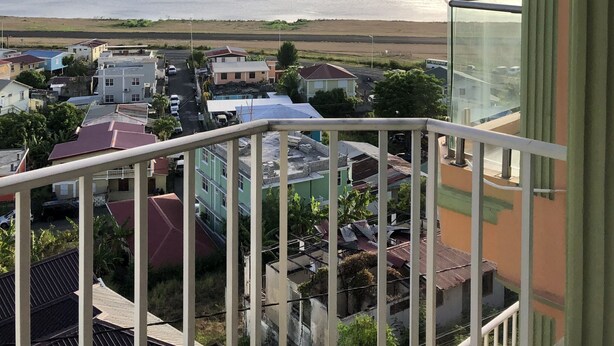 A balcony with a view of a beach and residential buildings. - Bayport Residence Inn (Roseau)