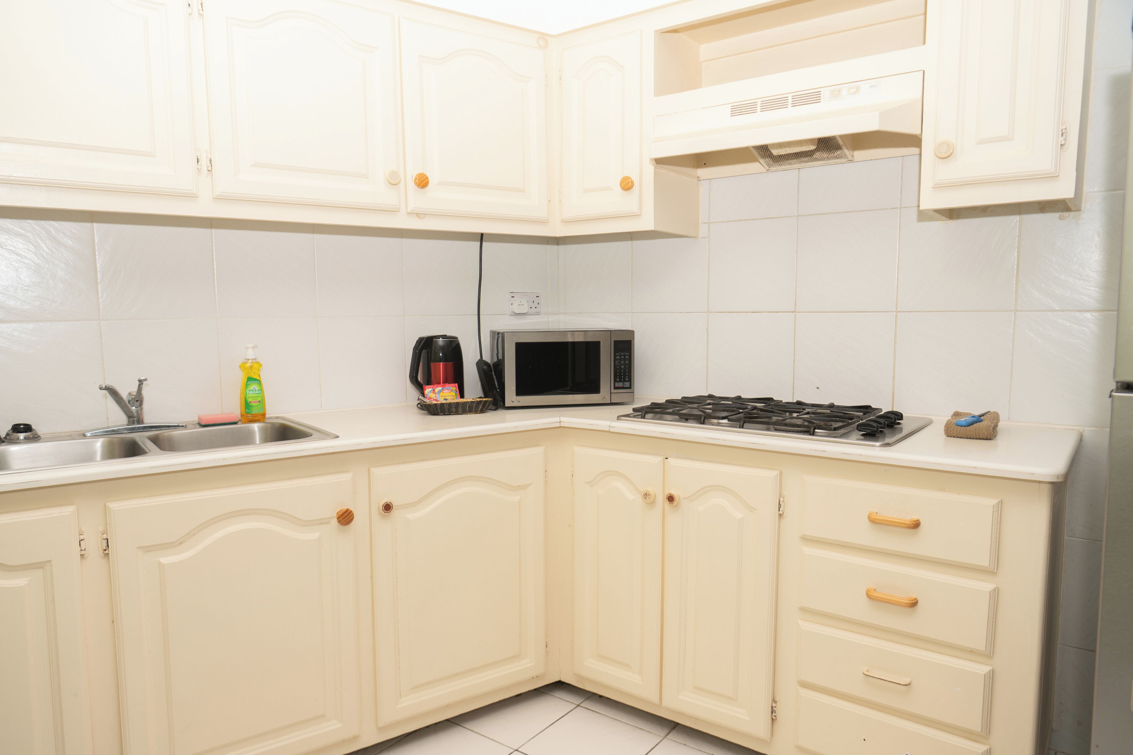 Una cocina con armarios blancos, un microondas, una estufa y un lavabo.