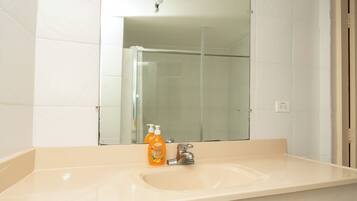 Un baño con lavamanos, espejo y ducha.