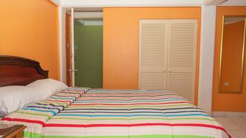 A bedroom with a bed, a nightstand, an open door leading to a green room, and a closet with sliding doors.