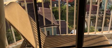 A balcony with a view of a residential area and the sea.