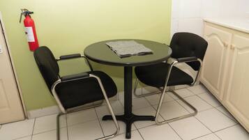 A small room with a round table and two chairs, a fire extinguisher on the wall, and a cabinet.