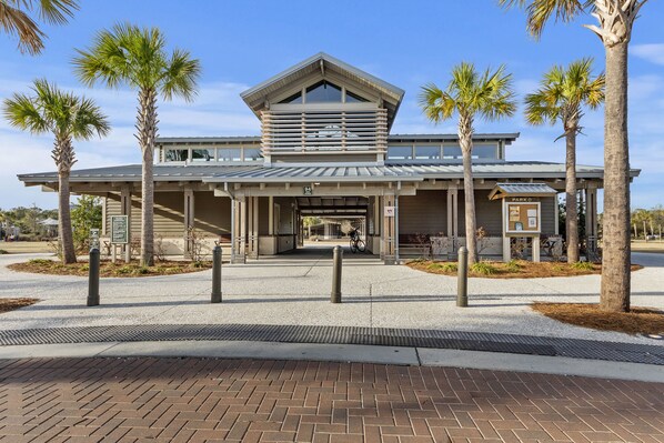 A modern building with a covered entrance, palm trees, and a bike parked outside. - Beautiful Spacious w/Indoor Outdoor Pool, Hot Tub, Tennis, Pickle Ball & Beach ! (Hilton Head Island)