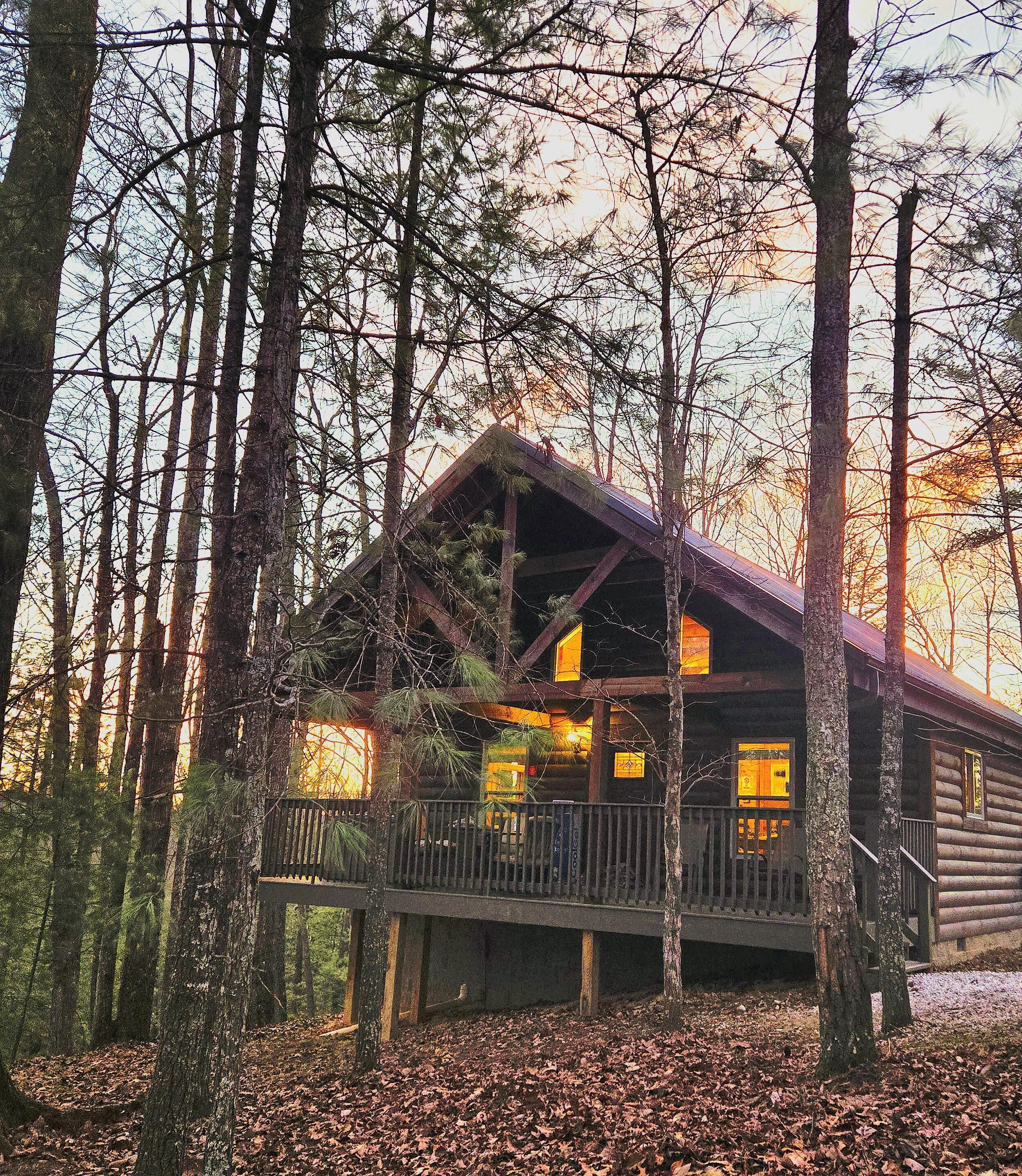 A cabin with a balcony, surrounded by trees.