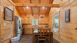 A wooden cabin interior with a kitchen, dining table, and chairs. - Secluded, forested, new cabin, 2-BR, 2-BA, Hot Tub, Wi-Fi, Smart TV's (Campton)