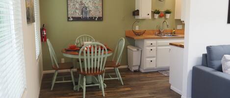 A compact living space with a dining area, kitchenette, and a grey sofa.