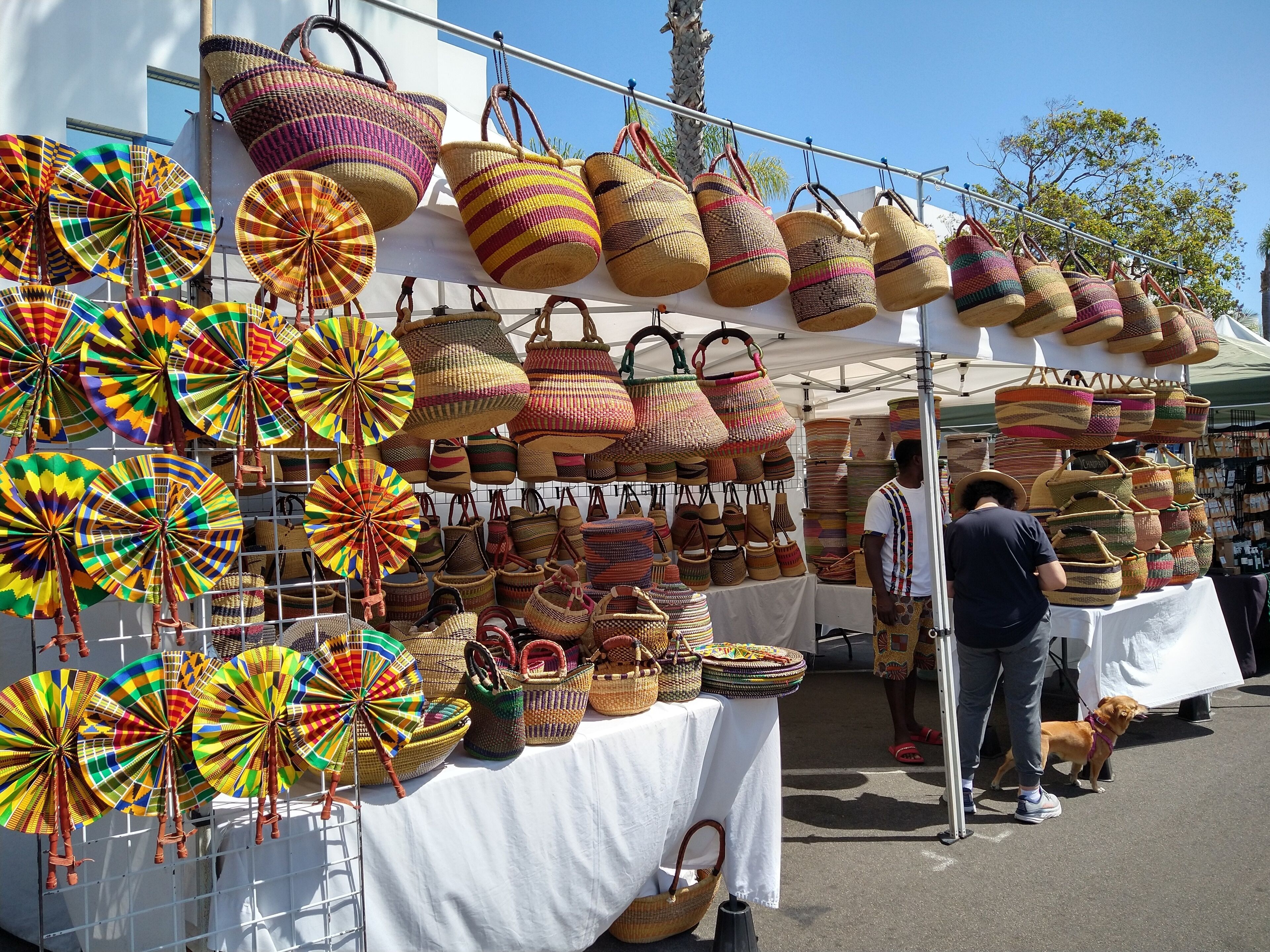 A market stall with various woven baskets and colorful woven items on display.