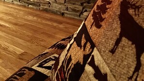 A stone fireplace with a fire, a wooden floor, and a patterned rug.