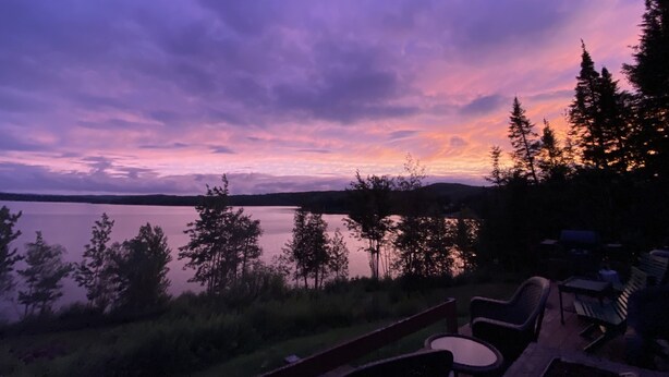 A lakeside view with a deck and outdoor seating area.