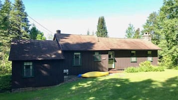 Escape to a cozy cabin surrounded by nature, with a well-maintained lawn and a kayak waiting to be explored.