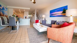 Ein modernes Wohnzimmer mit einer Couch, Sesseln, einem Couchtisch und einem Essbereich mit Stühlen und einem Tisch.