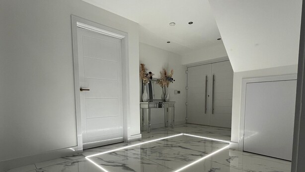 A hallway with a marble floor, white doors, and a vase with flowers on a table. - Cheerful 4 Bedroom Luxury house with free parking (Halesowen)