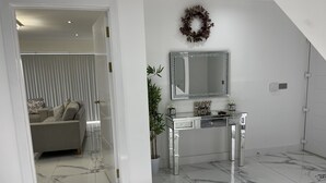 A modern interior with a marble floor, a glass console table, a mirror, and a decorative wreath. - Cheerful 4 Bedroom Luxury house with free parking (Halesowen)
