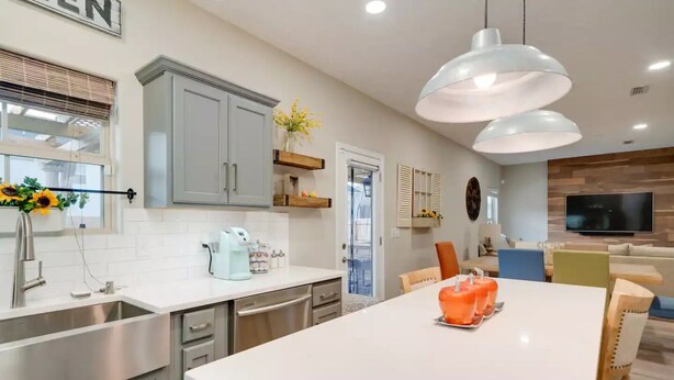 Una cocina moderna con una isla central, electrodomésticos de acero inoxidable e iluminación colgante.