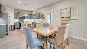 Una cocina moderna con armarios grises, un microondas y un lavabo. Hay una zona de comedor con una mesa y sillas de madera.