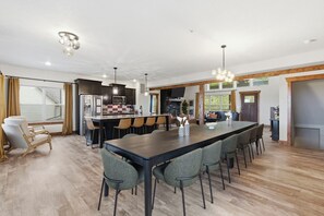 Una cocina amplia con una isla grande, electrodomésticos modernos y un comedor con una mesa larga y sillas.