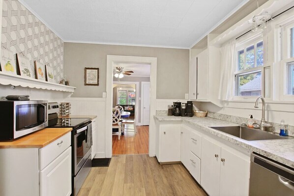 A kitchen with white cabinets, a microwave, a coffee maker, and a sink.