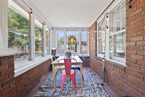 Relax in this serene sunroom with a table, chairs, and a potted plant.