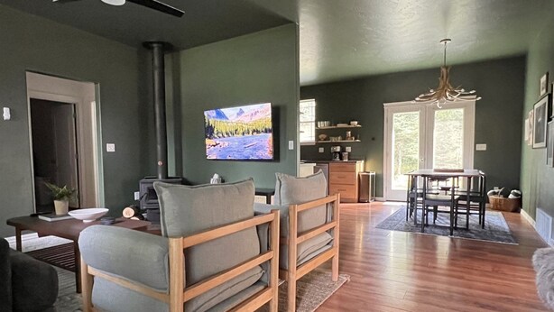 A modern living room with a fireplace, a television, and a dining area with a chandelier. - Cl113 Moonstone Acre (Columbia Falls)