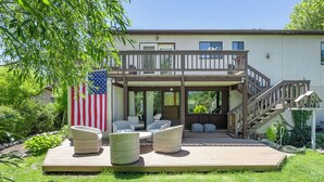 Uma casa de dois andares com varanda, área de estar externa e uma bandeira americana.