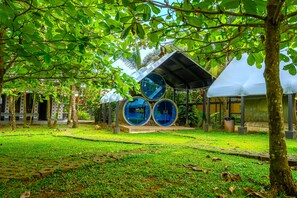 A garden with a unique structure featuring cylindrical elements and a covered area.